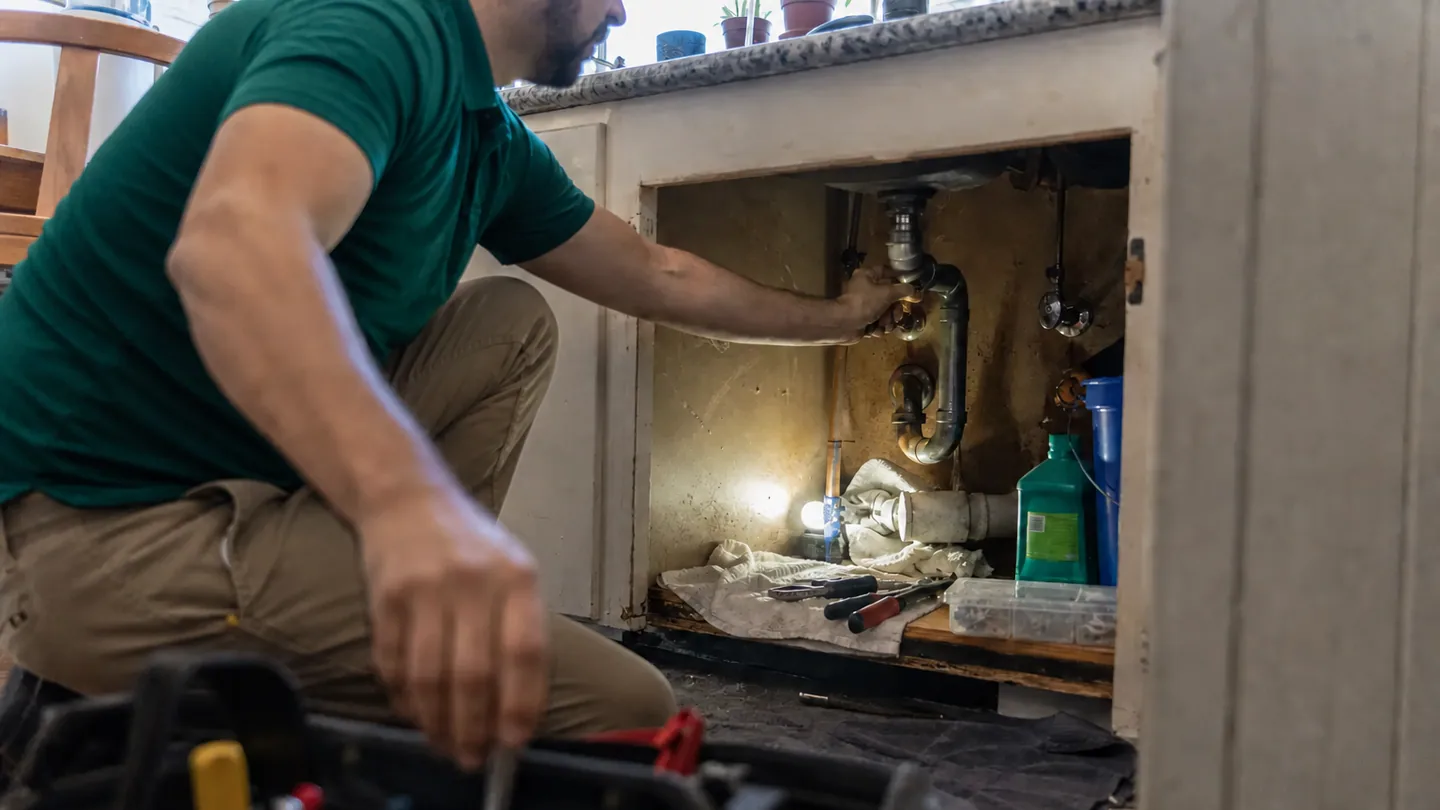 Paloma Pro technician repairing plumbing beneath a household sink